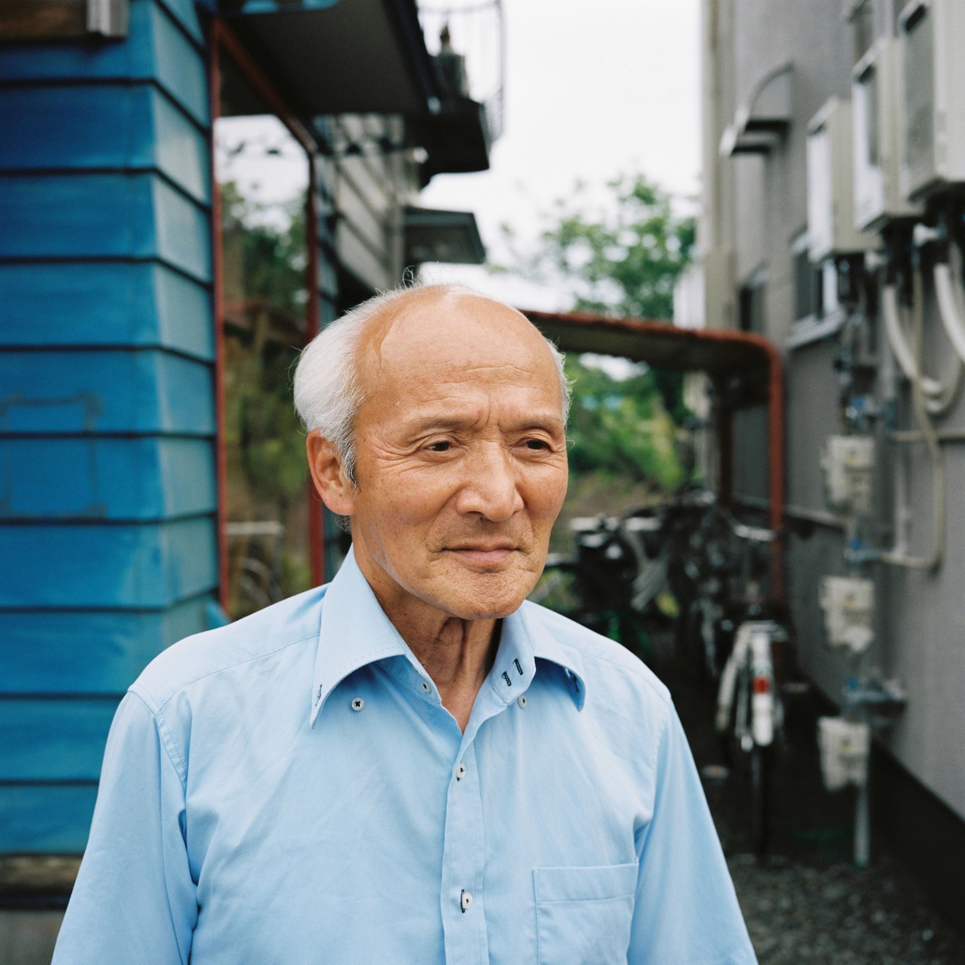 a man wearing a blue shirt standing in front of a building